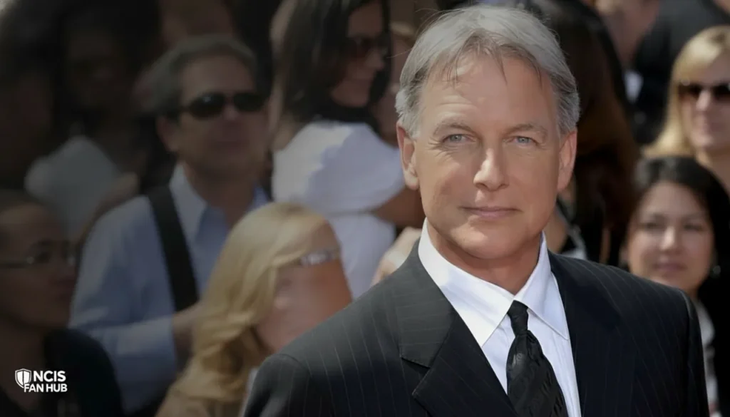 A close-up headshot of actor Mark Harmon, portraying Leroy Jethro Gibbs, with graying hair, blue eyes, and wearing a pinstripe suit and tie.