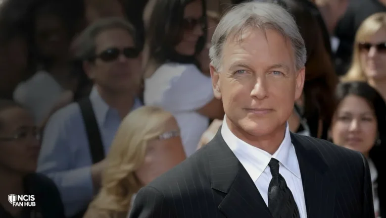 A close-up headshot of actor Mark Harmon, portraying Leroy Jethro Gibbs, with graying hair, blue eyes, and wearing a pinstripe suit and tie.