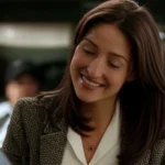 Sasha Alexander as Kate Todd smiling in NCIS windbreaker, standing with a male colleague outdoors