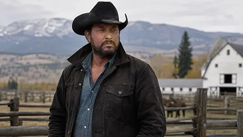 Rip Wheeler standing on the Yellowstone ranch with mountains and a barn behind him