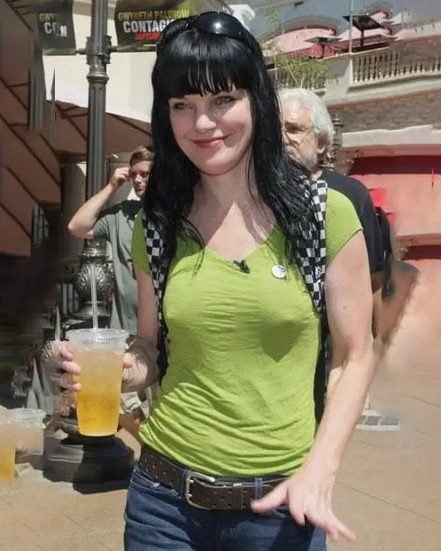 Pauley Perrette smiling in a green shirt, jeans and sunglasses at an outdoor public appearance