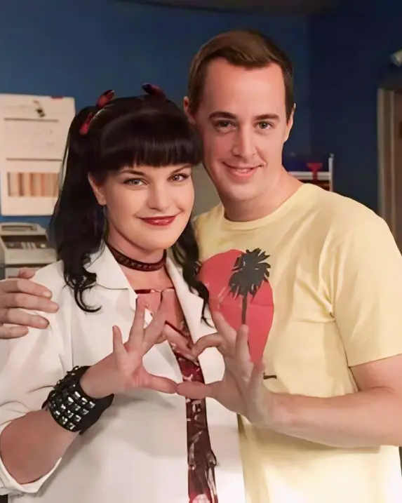 Pauley Perrette and Sean Murray posing together in Abby’s NCIS lab and making a heart shape with their hands