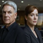 Harmon as Agent Gibbs and Lauren Holly as Director Jenny Shepard standing back-to-back in the NCIS headquarters with a hint of Paris in the background