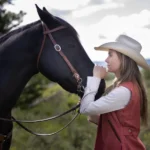 Amber Marshall standing beside her horse on the ranch, reflecting her real-life connection with animals and her Heartland character, Amy Fleming.