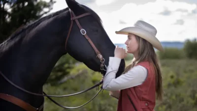 Amber Marshall standing beside her horse on the ranch, reflecting her real-life connection with animals and her Heartland character, Amy Fleming.