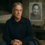 Actor Mark Harmon sits on a wooden workbench on the NCIS soundstage, boat hull blurred behind him, in neutral daylight