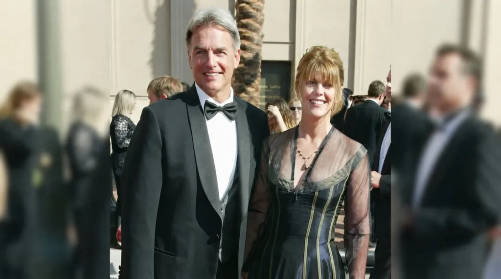 Mark Harmon in a tuxedo smiling with his wife Pam Dawber in a black gown on a red carpet.